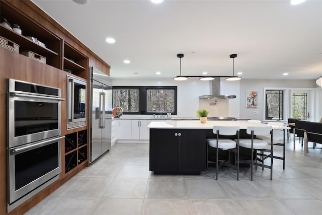 kitchen featuring a large island, open shelves, stainless steel appliances, light countertops, and wall chimney range hood