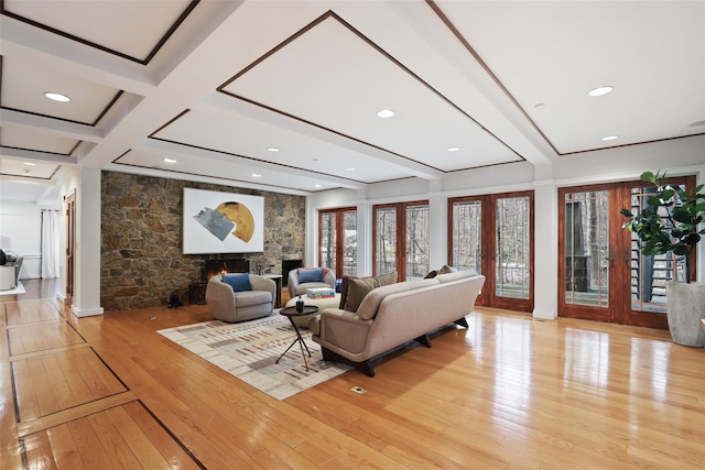 living room with light wood-style flooring, a fireplace, coffered ceiling, french doors, and beamed ceiling