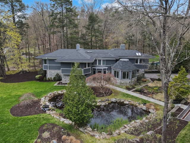 54 Lincoln Ave, Rye Brook, NY 10573 - rear view of property with a small pond, stone siding, a chimney, and a lawn