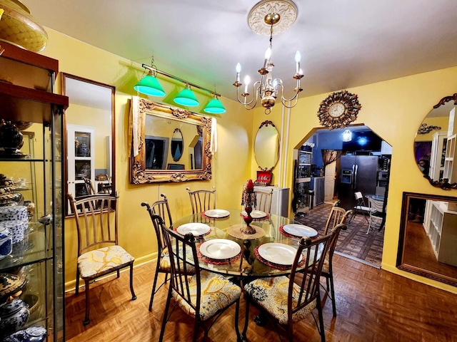 dining space featuring arched walkways, a notable chandelier, and baseboards