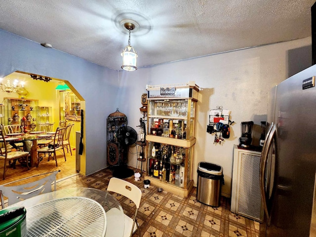 interior space with arched walkways, tile patterned floors, a textured ceiling, and freestanding refrigerator