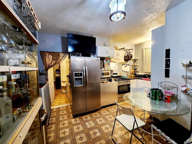 kitchen featuring under cabinet range hood, a textured ceiling, white cabinetry, stainless steel appliances, and light floors