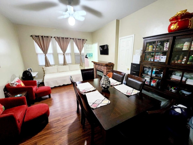 dining area with a fireplace, a ceiling fan, and wood finished floors