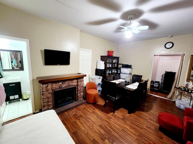 office with a ceiling fan, wood finished floors, and a fireplace