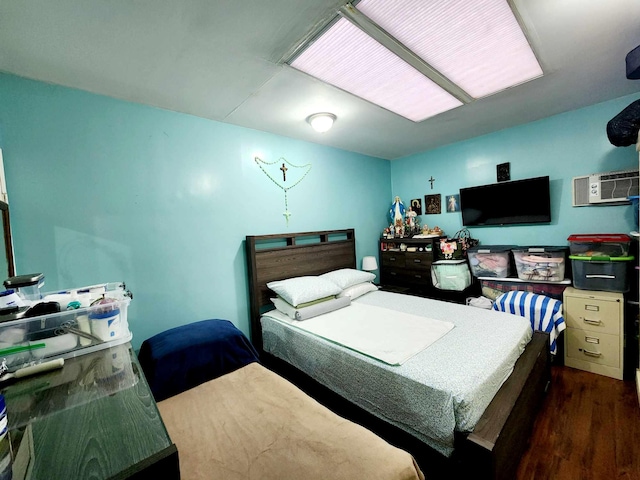 bedroom with an AC wall unit and wood finished floors