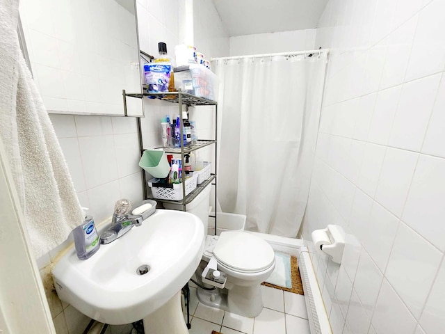 bathroom with tile patterned flooring, toilet, a stall shower, tile walls, and a sink