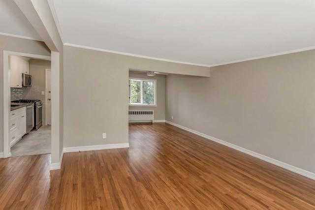 empty room with baseboards, ornamental molding, light wood-type flooring, and radiator