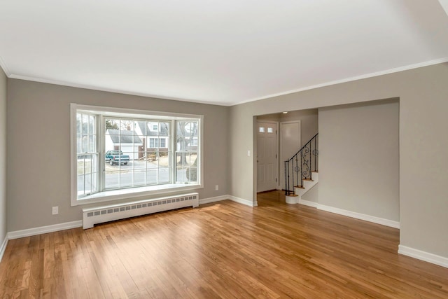 empty room featuring baseboard heating, wood finished floors, and baseboards