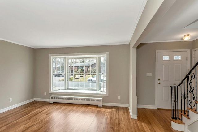 entryway with stairs, light wood finished floors, baseboards, and radiator