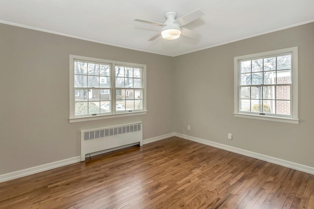 spare room featuring radiator, baseboards, ornamental molding, and wood finished floors