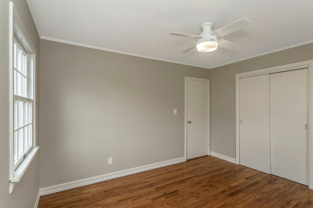 unfurnished bedroom with a closet, baseboards, wood finished floors, and ornamental molding