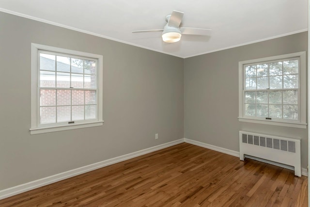 spare room featuring ornamental molding, baseboards, radiator heating unit, and wood finished floors