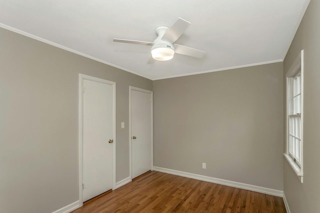 spare room featuring crown molding, wood finished floors, and baseboards