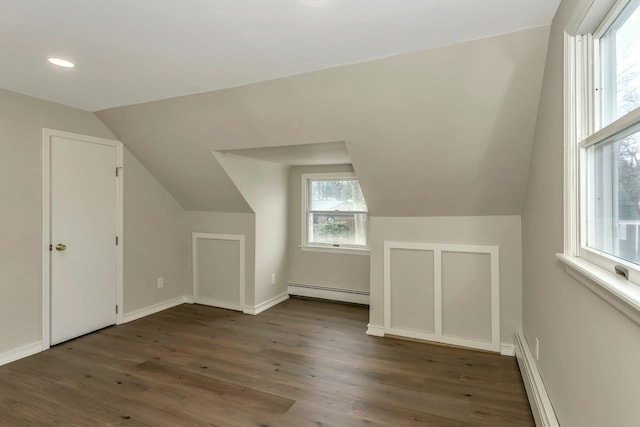 additional living space featuring dark wood-style floors, baseboard heating, lofted ceiling, and baseboards