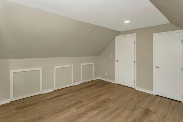 additional living space featuring light wood-type flooring, baseboards, and lofted ceiling