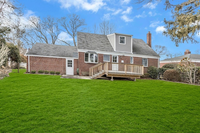 rear view of property featuring brick siding, a lawn, and a wooden deck