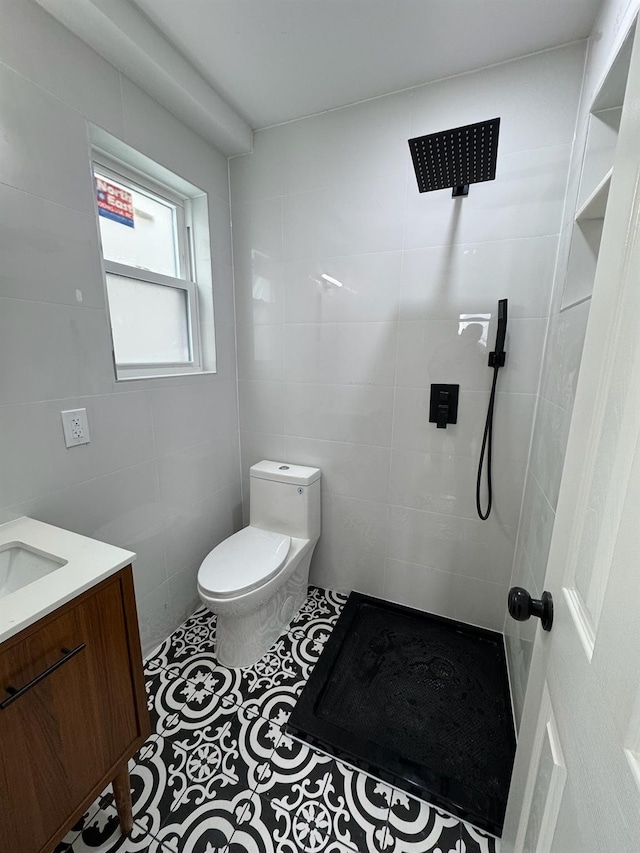 bathroom with a tile shower, toilet, tile patterned floors, and tile walls