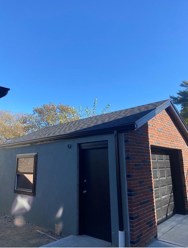 exterior space with a garage, brick siding, and a shingled roof