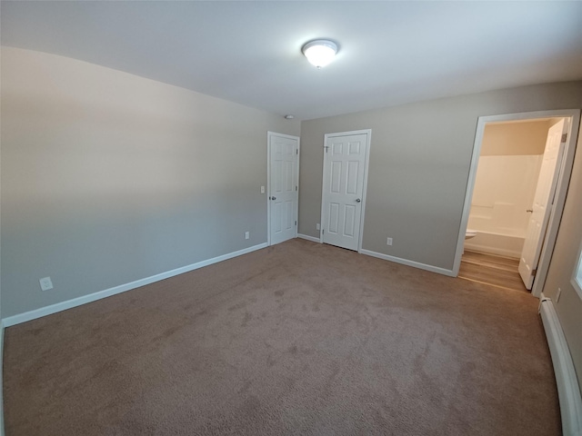 unfurnished bedroom featuring a baseboard heating unit, connected bathroom, and carpet flooring