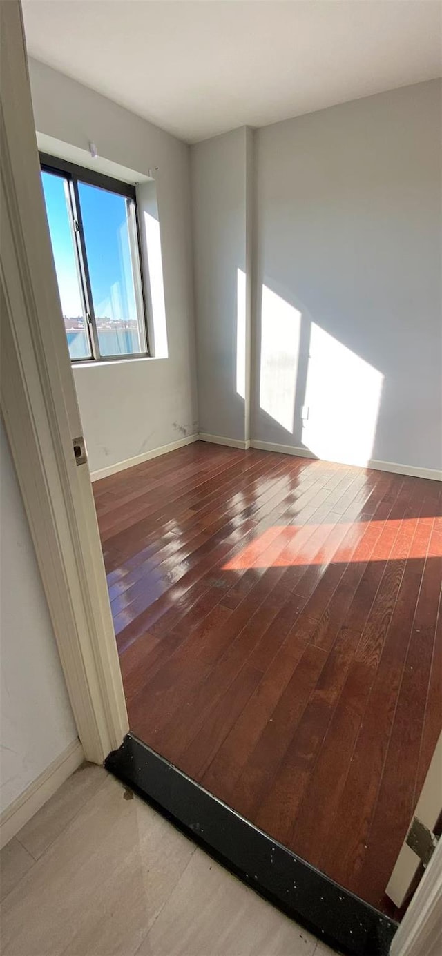 empty room featuring baseboards and wood-type flooring