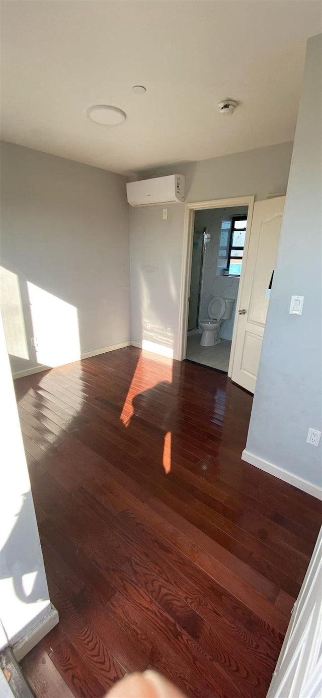 interior space featuring baseboards, wood finished floors, and a wall mounted AC