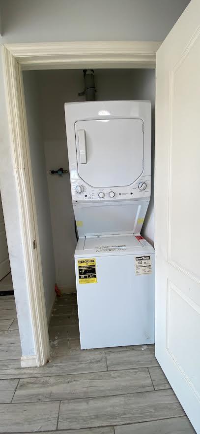 laundry room featuring laundry area, stacked washer / drying machine, and light wood-style floors