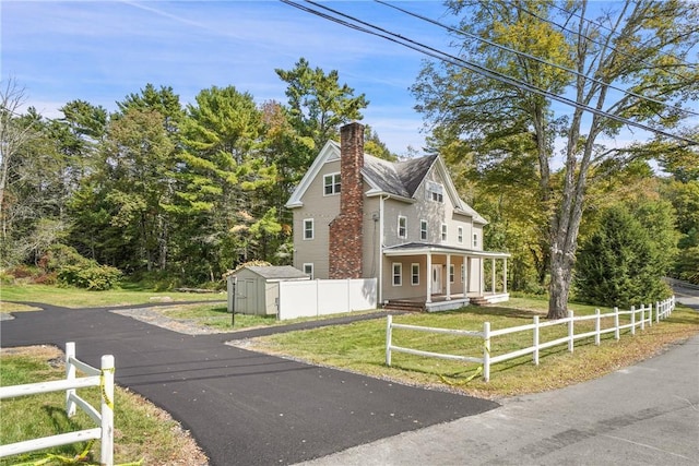 view of front of property featuring a front yard and a storage shed