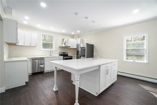 kitchen featuring pendant lighting, wall chimney range hood, sink, stainless steel appliances, and a center island with sink