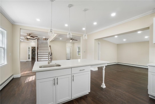 kitchen with sink, decorative light fixtures, ornamental molding, an island with sink, and white cabinets