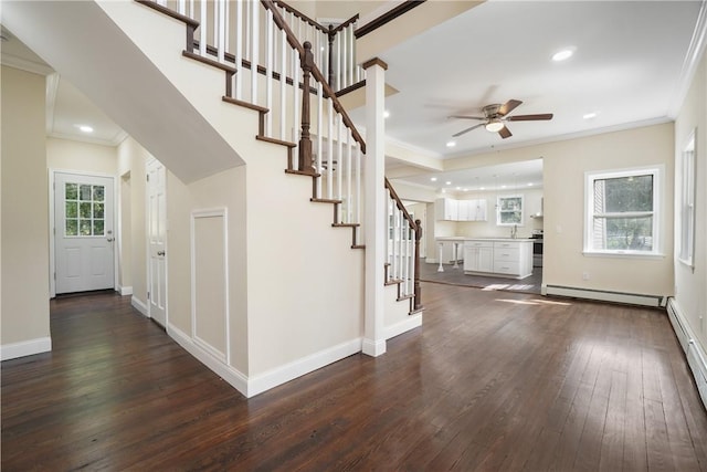 stairs with baseboard heating, ceiling fan, crown molding, and hardwood / wood-style floors