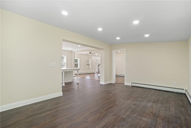 empty room featuring ceiling fan, dark hardwood / wood-style flooring, and a baseboard heating unit