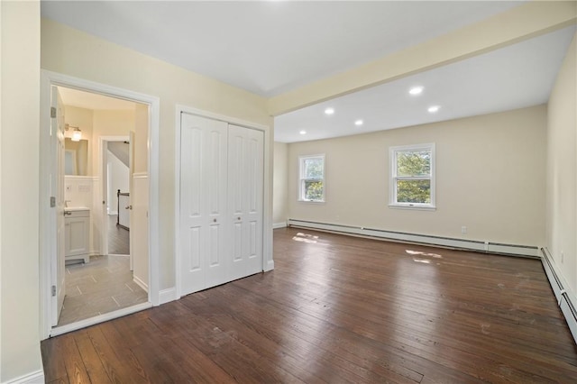 unfurnished bedroom with a baseboard radiator, wood-type flooring, and a closet