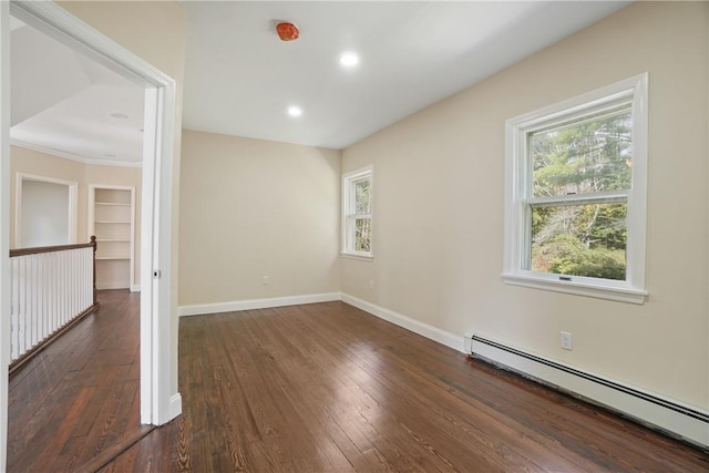 spare room with baseboard heating, dark wood-type flooring, and built in shelves