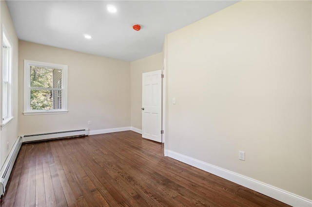 empty room featuring dark wood-type flooring and a baseboard heating unit