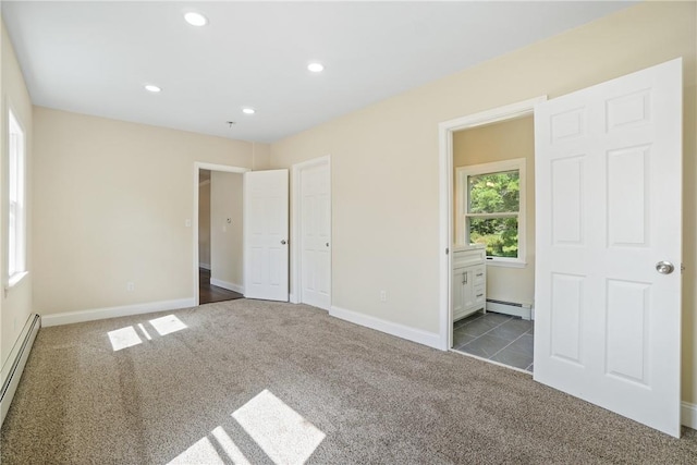 unfurnished bedroom with a baseboard radiator, ensuite bath, and dark colored carpet