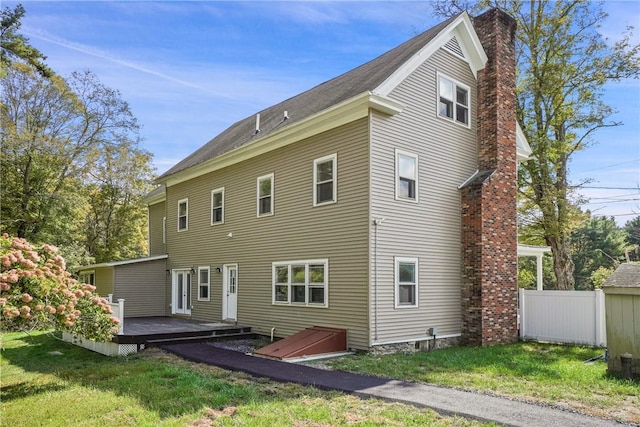 back of house featuring a lawn and a deck