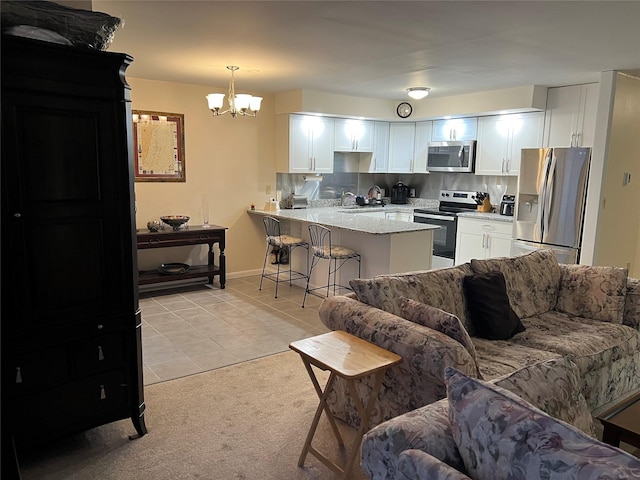 kitchen with stainless steel appliances, a peninsula, white cabinets, open floor plan, and a kitchen bar