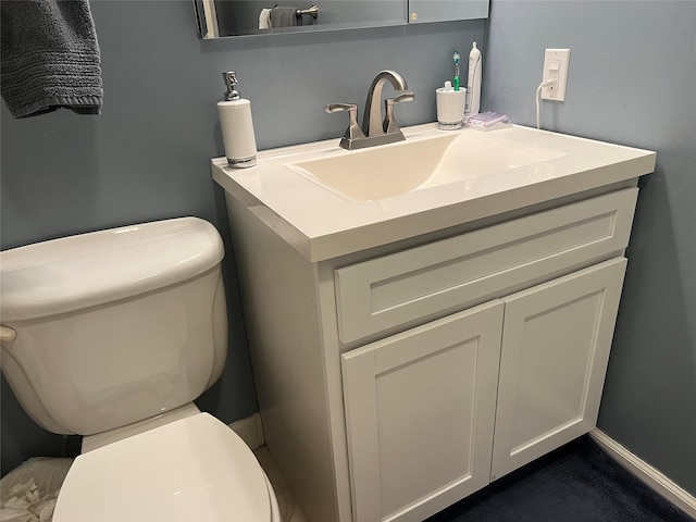 bathroom featuring baseboards, vanity, and toilet