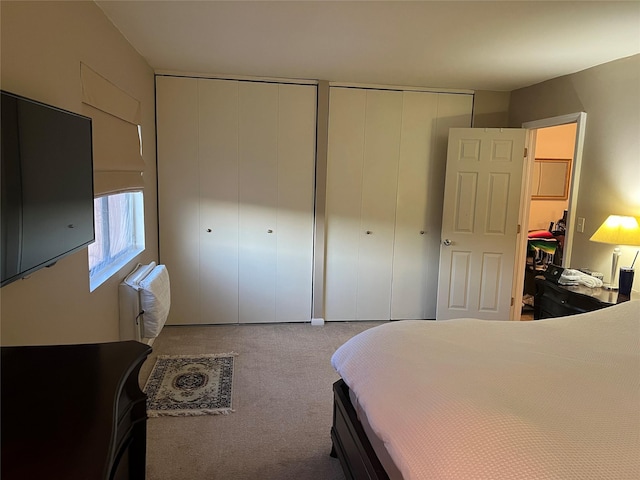 carpeted bedroom with radiator heating unit and multiple closets