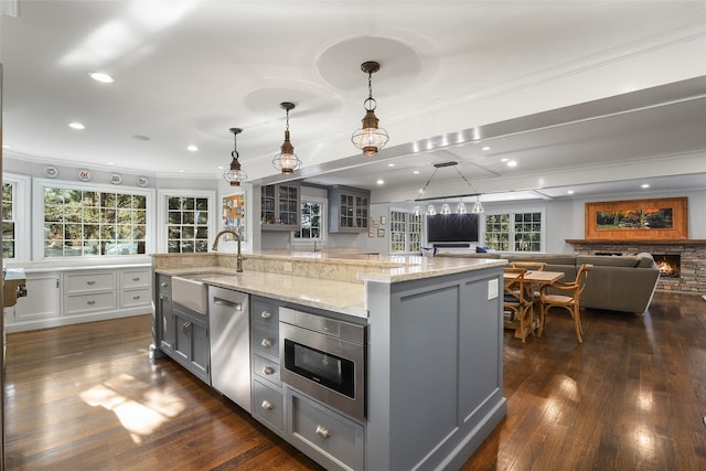 kitchen with an island with sink, appliances with stainless steel finishes, sink, and decorative light fixtures