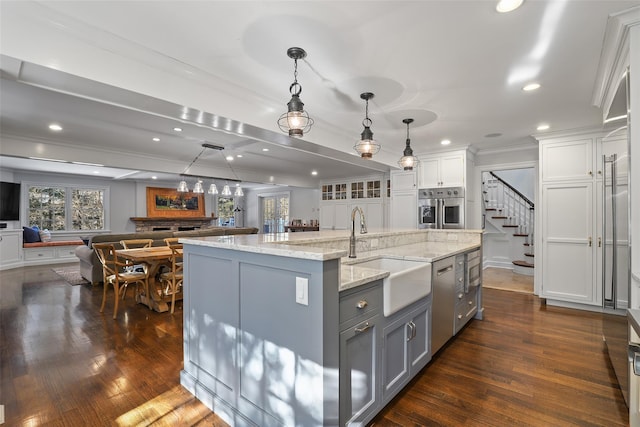 kitchen featuring gray cabinets, decorative light fixtures, sink, a large island with sink, and ornamental molding