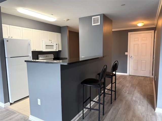 kitchen with kitchen peninsula, white cabinets, white appliances, and light hardwood / wood-style flooring