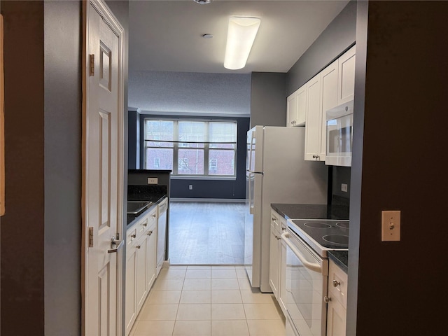 kitchen featuring dark stone countertops, white appliances, white cabinets, and light tile patterned flooring