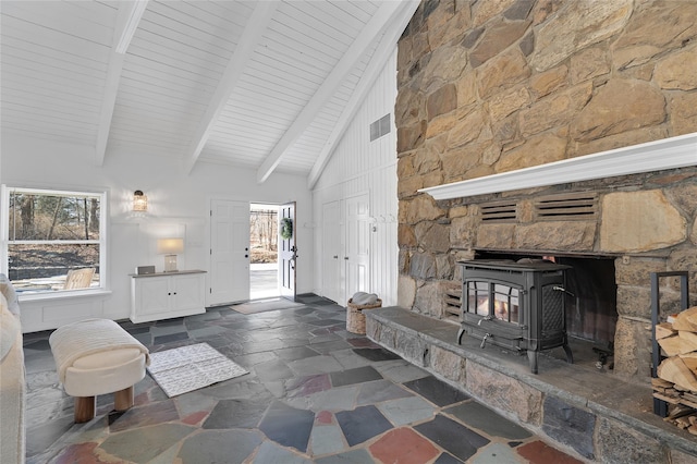 living area with plenty of natural light, beam ceiling, visible vents, and stone tile flooring