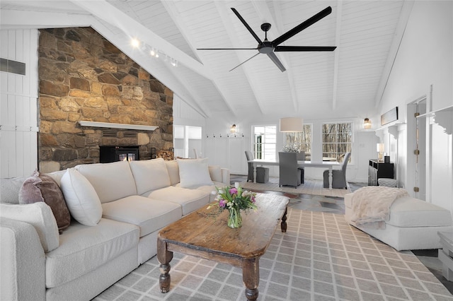 living area featuring visible vents, a ceiling fan, a stone fireplace, high vaulted ceiling, and beam ceiling