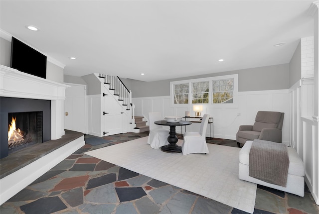 living room with stairs, a lit fireplace, wainscoting, and recessed lighting