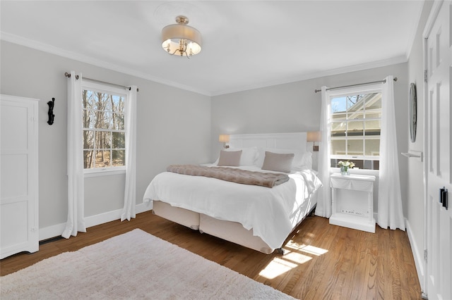 bedroom featuring baseboards, multiple windows, wood finished floors, and crown molding