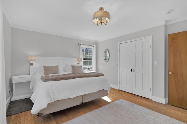 bedroom with crown molding, a closet, baseboards, and wood finished floors