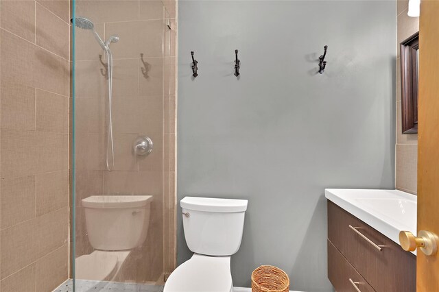 bathroom with vanity, a tile shower, and toilet