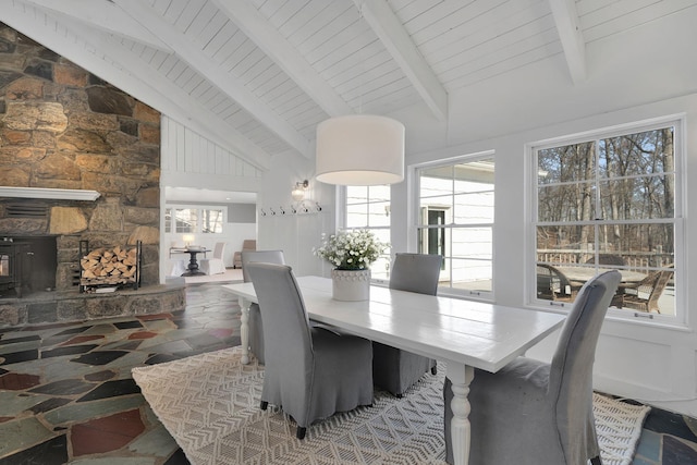 dining area with wood ceiling, high vaulted ceiling, a wood stove, and beam ceiling